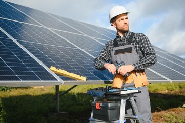 Expert is inspecting quality of a solar batterys. Worker in uniform and helmet with equipment. Ecology power conservation concept.