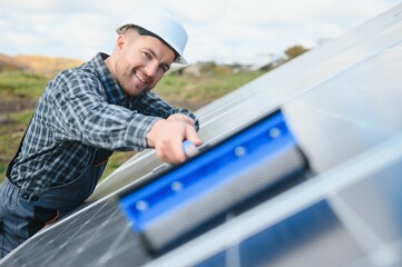 technician operating and cleaning solar panels at generating power of solar power plant; technician...