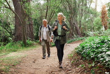 Nature, forest and senior couple hiking for health, wellness and cardio exercise outdoor. Travel, trail adventure and elderly man and woman in retirement trekking in the woods for a hobby or workout. - obrazy, fototapety, plakaty