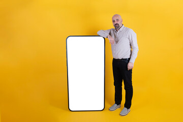 Huge smartphone mock up, full body size male leaning huge smartphone mock up. Advertising concept idea, copy space. Yellow background. Modern mobile phone application. Businessman recommending app.