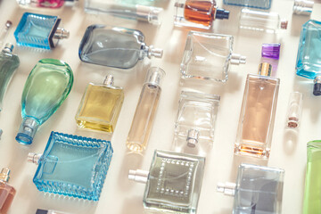 Perfumery, cosmetics and beauty industry background. A lot of transparent bottles of perfume and cologne and toilet water lie neatly on a beige background or a showcase.