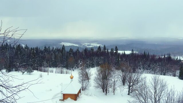 View of the chapel near the Belogorsky St. Nicholas Orthodox Missionary Monastery. Winter forest. The temple on the hill in winter. Russia, Perm Krai, Belaya Gora. 4K