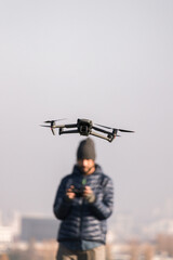 Fototapeta na wymiar Man with a beard and unfocused pilots his gray drone outside of Berlin