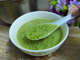 Green tapioca pearl porridge with coconut milk, served in a white bowl. Ready to eat.