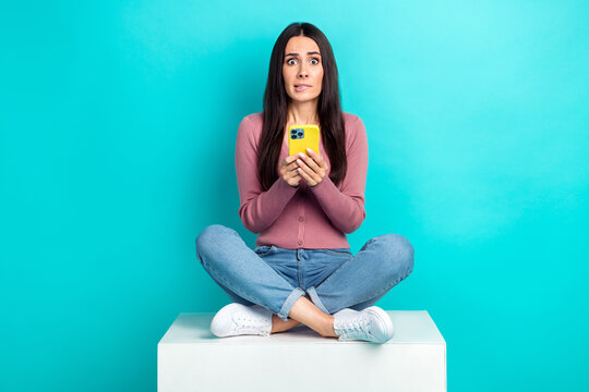 Full length photo of confused lady nervous bite lips hold her apple iphone terrified try dont remember password isolated on cyan color background
