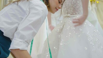 Caucasian woman designer or wedding dress shop owners try to help choose a bridal gown and try on a wedding dress at the wedding studio, The beautiful bride smiles happily in her beautiful dress.