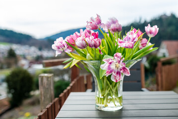 A bouquet of tulips in a glass vase on a table outdoors