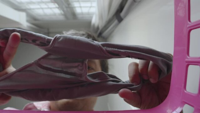 Asian man checking underpants before put it in a clothes basket.