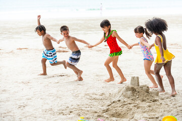 Group of Diversity little child boy and girl friends running and playing sea water at tropical beach together on summer vacation. Happy children kids enjoy and fun outdoor lifestyle on beach holiday.