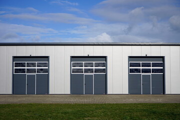Moderne Architektur eines Gewerbebau in Grau und Silber mit modernem Sektionaltor vor blauem Himmel...