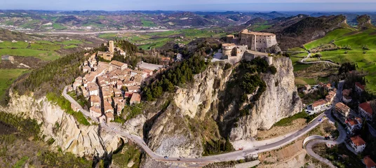 Schilderijen op glas Unique beautiful places of Italy. Emilia Romagna region. Aerial drone view of impressive San Leo medieval castle located in the top of sandstone rock and village © Freesurf