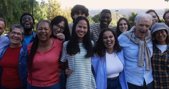 Group of multigenerational people smiling in front of camera - Multiracial friends with different ages having fun together at city park 