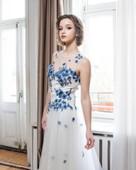 A woman in a white dress with blue flowers