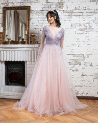 Woman in a pink dress standing in front of a brick wall