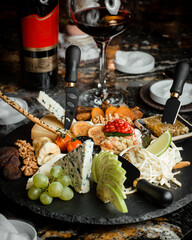 Many different varieties of cheese, dried fruits, fruits, nuts and honey with a smoke effect on the table