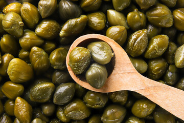 Capers in a wooden spoon, background. Top view