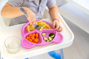 Obraz na płótnie Canvas The child eats pasta and vegetables. Selective focus.