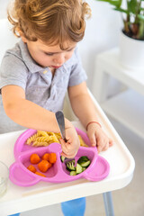 Obraz na płótnie Canvas The child eats pasta and vegetables. Selective focus.