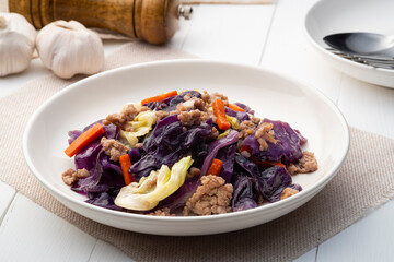 Stir fried minced pork, red cabbage and green cabbage with fish sauce in white plate