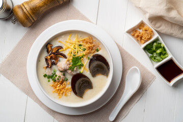 Rice porridge ,Congee with preserved eggs, minced pork, mushroom and ginger in white bowl