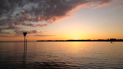 Silhouette of a paddler in the sunset at the very back of the picture and dramatic cloud formation