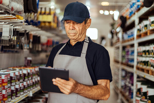 Elderly man working in a hardware store using digital tablet. Small business concept.