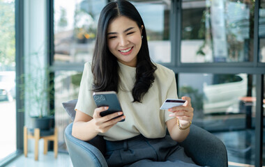 Asian girl shopping online holding credit and using smartphone enter their card number in the mobile phone app to purchase and payment in internet store