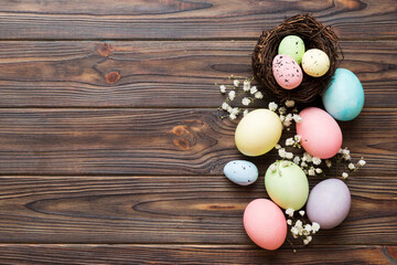 Fototapeta na wymiar Happy Easter composition. Easter eggs in basket on colored table with gypsophila. Natural dyed colorful eggs background top view with copy space