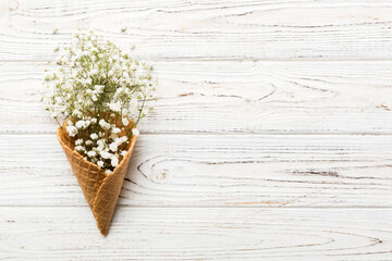Waffle cone with beautiful gypsophila flowers on color background. summer concept. Copy space top view