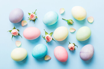 Happy Easter. Easter eggs on colored table with yellow roses. Natural dyed colorful eggs background top view with copy space