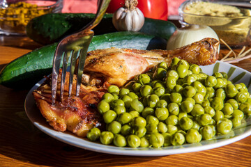 Roasted delicious chicken with vegetables...peas...wooden table