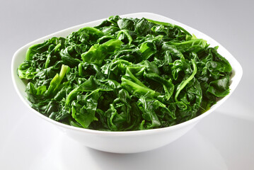 Gegarter Blattspinat in Porzellanschuessel als Freisteller