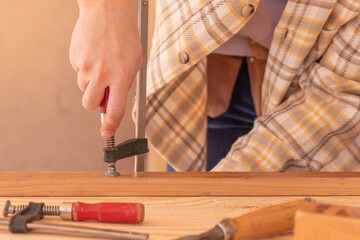 Craftsman with clamps working with wood. Crop unrecognizable male carpenter installing clamps and vices for gluing wooden details on workbench