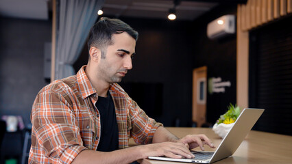 He is checking work and talking staff, through video call on laptop computer, with serious expression gestures that are not satisfied with work that must be resolved repeatedly.