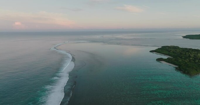 Aerial Shot Of Waves Splashing Towards Green Island, Drone Flying Backwards On Sunset - Nadi, Fiji