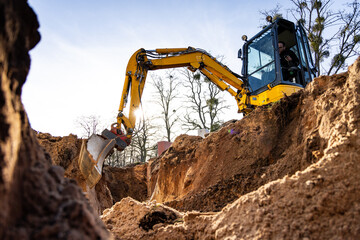 Excavator digging a hole into the ground - obrazy, fototapety, plakaty