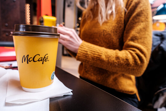 Woman Sitting Inside A  McDonalds Restaurant With A Take Away Coffee
