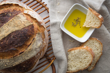 Close up of freshly baked round artisan bread, olive oil with oregano on the side which a piece pf...