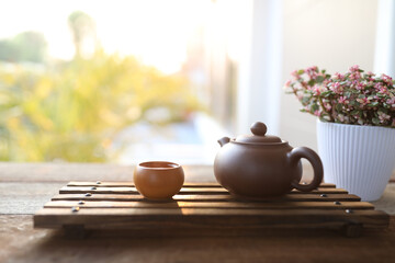 earthenware teapot and small tea cup and Portulacaria afra on wooden tray