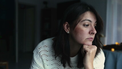 One thoughtful woman adjusting hair at home with pensive expression