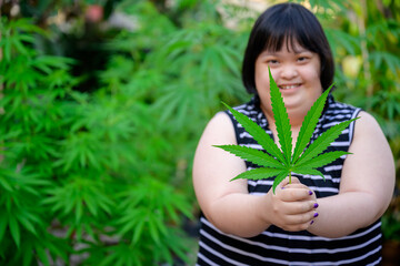 Woman with Down syndrome holding a marijuana leaf. She is mentally disabled standing with a...