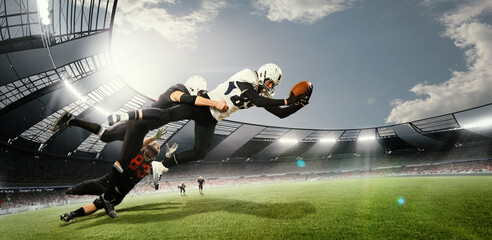 During game. American football players in action, catching ball at open air 3D stadium on daytime...