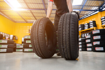new tires Car mechanic brings new tires in stock 2 lines to the tire shop to change the wheel of...