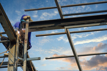 Male welder welding steel at construction site construction worker working on a steel roof structure