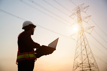 1 Portrait of an male electrical engineer standing at a power station Use the computer to view the power generation planning work at the high-voltage pylons.