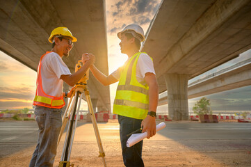 Asian male engineer team working with theodolite to mark concrete bridge piles at construction site...