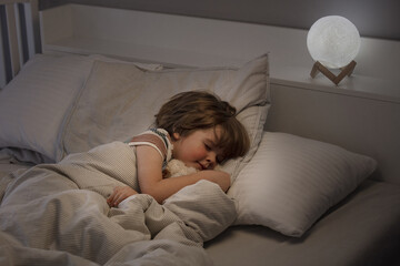 Little boy sleeping in bed. At night, the toddler sleeps in his room. Lifestyle.
A child's healthy...