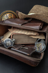 The Vintage Music Notes,the Old Book,the Analog Pocket Watch, the Key and the Antique Iron Padlock are in the Old Brown Leather Bag.The Straw fedora Hat and the Globe are on them with Dark Background.