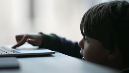 Candid small boy using laptop computer. Child close up face touching trackpad looking at screen