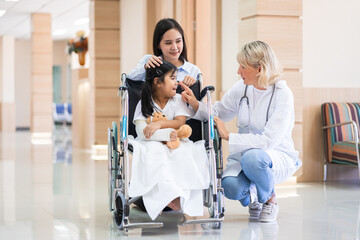 Female pediatrician doctor and child patient on wheelchair with her mother in the health medical...